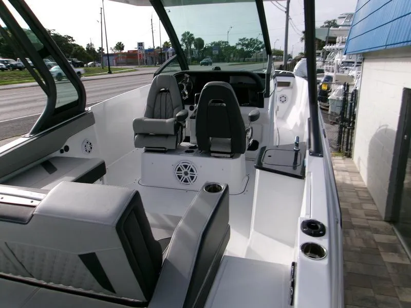 Slide: The Image of 2025 Monterey Elite 27 OB boat interior with modern seating and dashboard, docked near a street. - 9