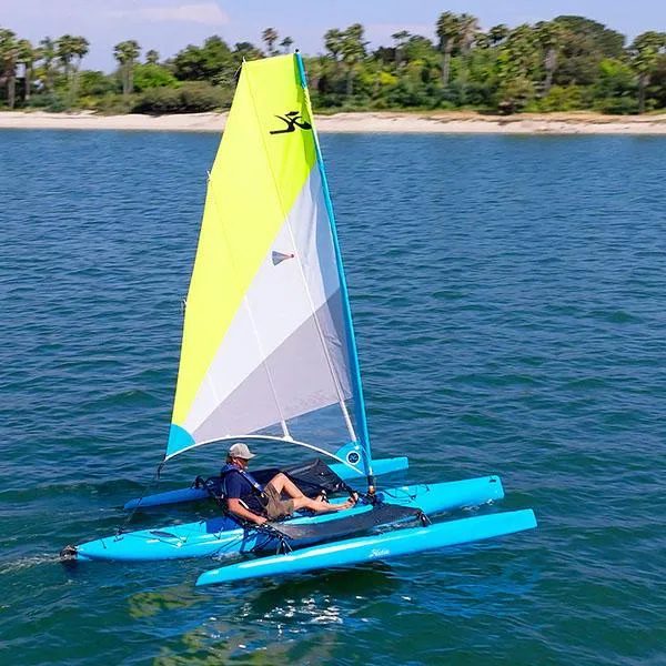 The Image of 2025 Hobie Adventure Island sailing on blue water near a lush shoreline. - 0