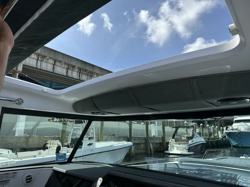 Slide: The Image of 2022 Axopar 37 XC CROSS CABIN interior view with open sunroof and docked boats. - 12