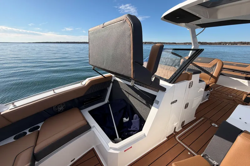 Slide: The Image of 2026 Cobalt R31 boat interior with open storage compartment, brown seating, and scenic water view. - 32