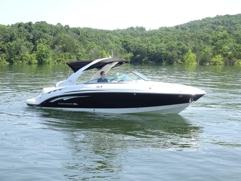 Slide: The Image of 2014 Chaparral 287 SSX boat cruising on a serene lake with lush green surroundings. - 1
