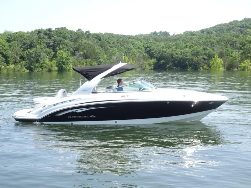 Slide: The Image of 2014 Chaparral 287 SSX boat on a serene lake with lush green background. - 2