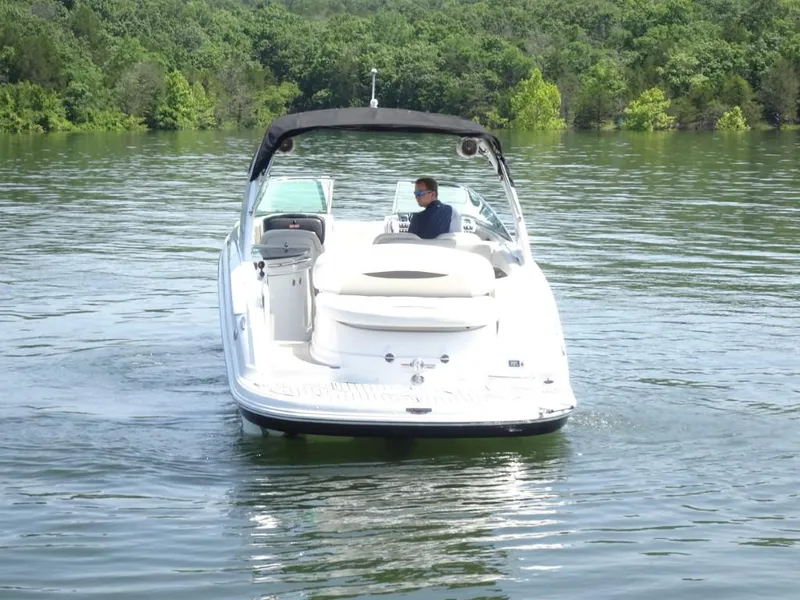 Slide: The Image of 2014 Chaparral 287 SSX boat cruising on a calm lake with lush green background. - 4