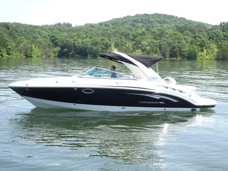 Slide: The Image of 2014 Chaparral 287 SSX boat cruising on a serene lake with lush green hills. - 7