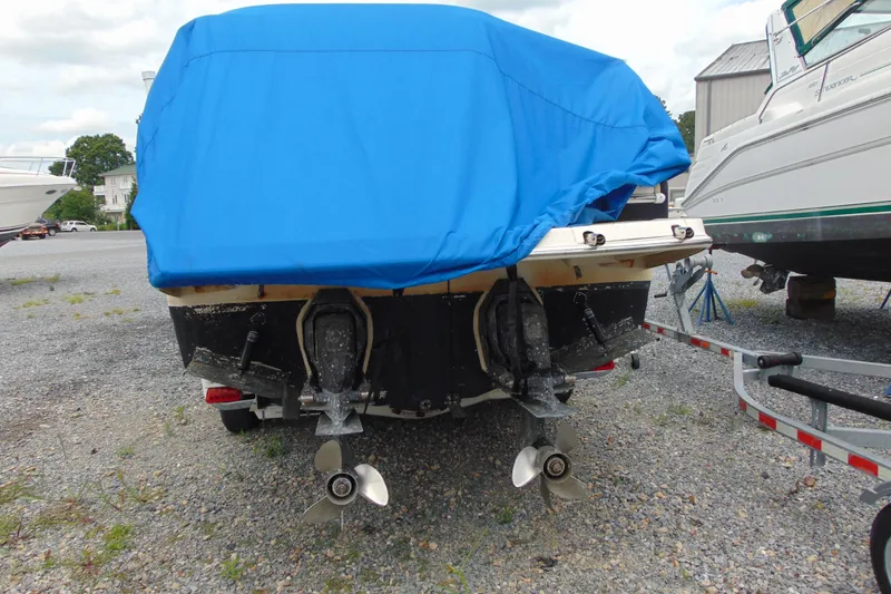 Slide: The Image of 2004 Regal Commodore 2765 boat with blue cover, dual propellers, parked on gravel. - 14