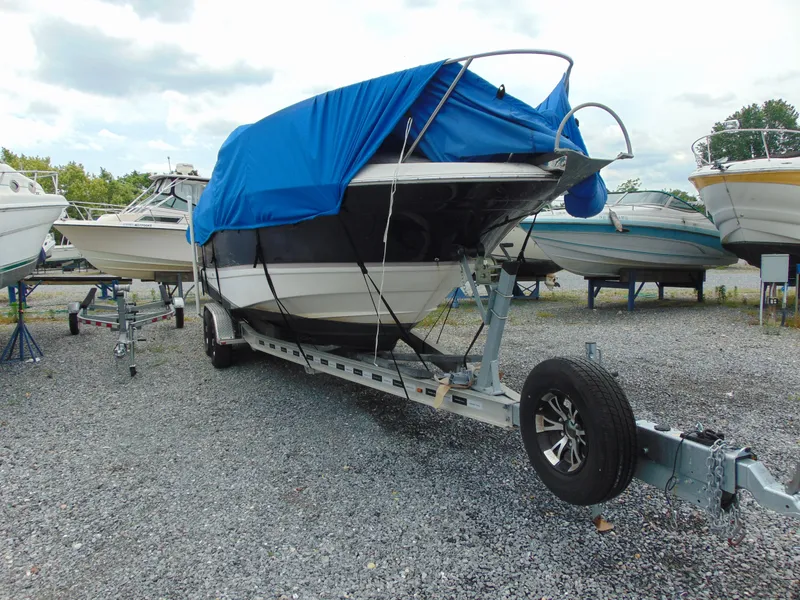 Slide: The Image of 2004 Regal 2765 Commodore boat on trailer, covered with blue tarp, parked on gravel. - 3