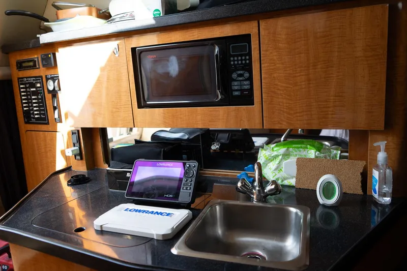 Slide: The Image of 2004 Regal Commodore 2765 boat interior with kitchenette, microwave, sink, and navigation equipment. - 32