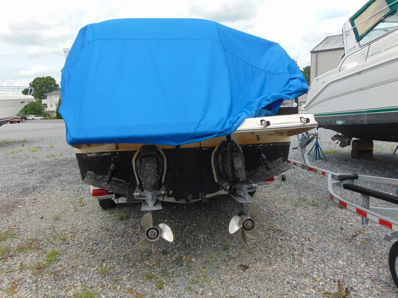Slide: The Image of 2004 Regal 2765 Commodore boat with blue cover, dual propellers, parked on gravel. - 4