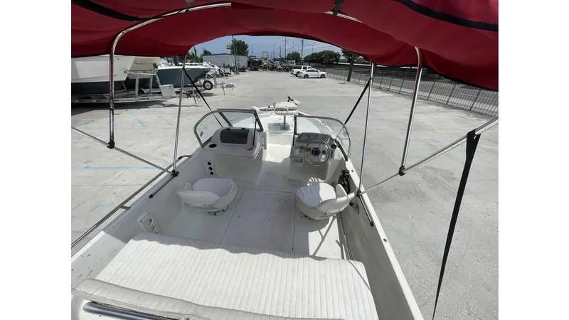 Slide: The Image of 2002 Bay Stealth 1880 boat with red canopy, dual seats, and open deck in a parking area. - 14