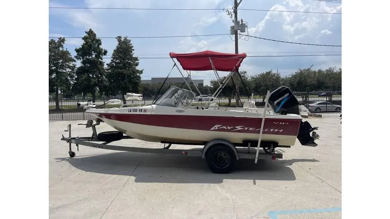 Slide: The Image of 2002 Bay Stealth 1880 boat with red canopy on trailer, parked outdoors. - 5
