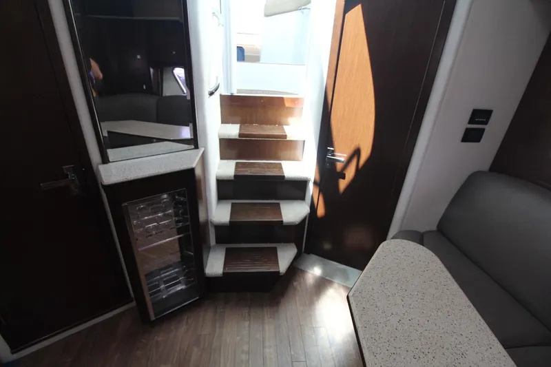 Slide: The Image of Interior of 2013 Cruisers Yachts 430 SC, featuring stairs, seating, and a compact fridge. - 15