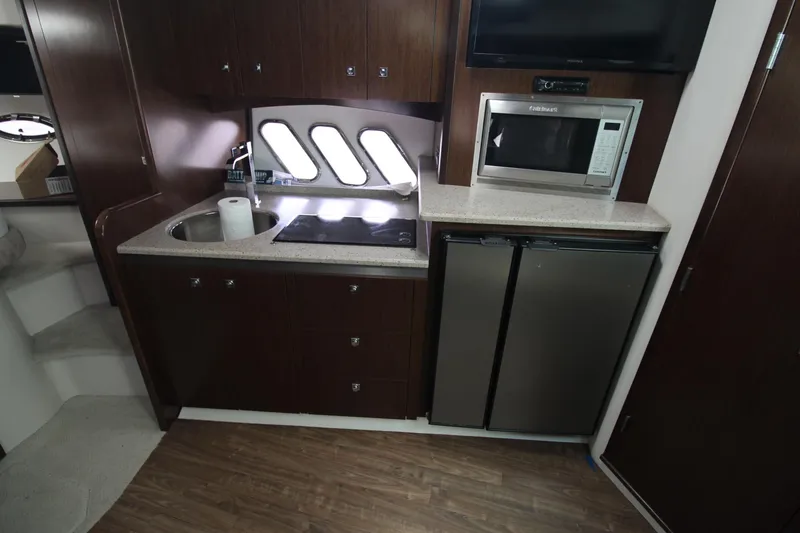 Slide: The Image of 2013 Cruisers Yachts 430 SC kitchen with sink, stove, microwave, and fridge. - 17