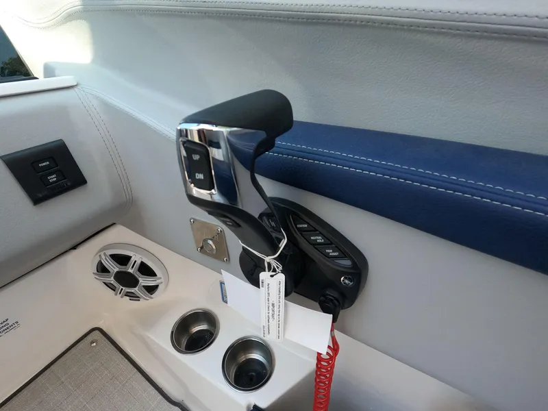 Slide: The Image of 2026 Regal LX6 boat throttle control with cup holders and speaker. - 14