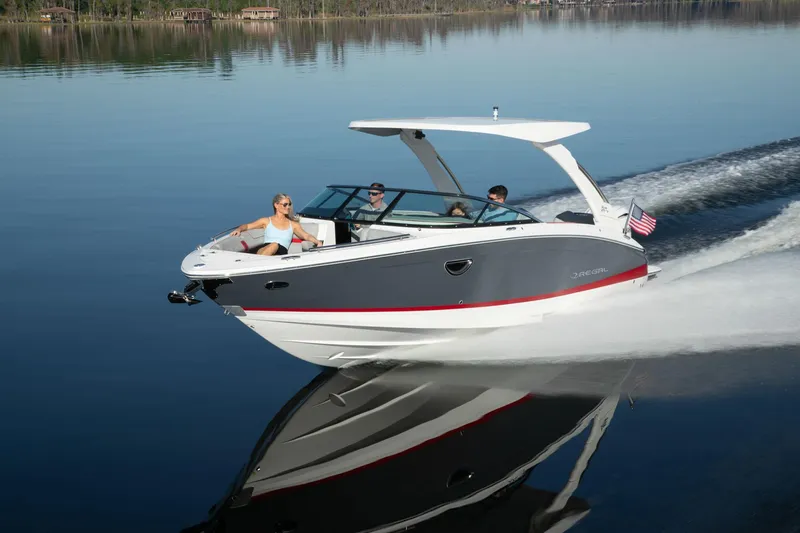 Slide: The Image of 2026 Regal LX6 boat cruising on a calm lake with passengers enjoying the ride. - 23