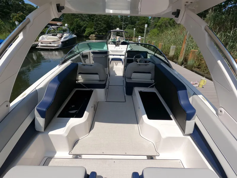 Slide: The Image of 2026 Regal LX6 boat interior with spacious seating, docked near lush greenery. - 9