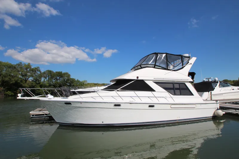 Slide: The Image of 1996 Bayliner 3988 Command Bridge Motoryacht docked on calm water under blue sky. - 0