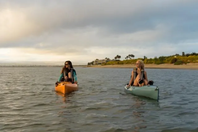 Slide: The Image of Two people kayaking on Hobie Revolution 11, 2025 model, in a serene coastal setting. - 3
