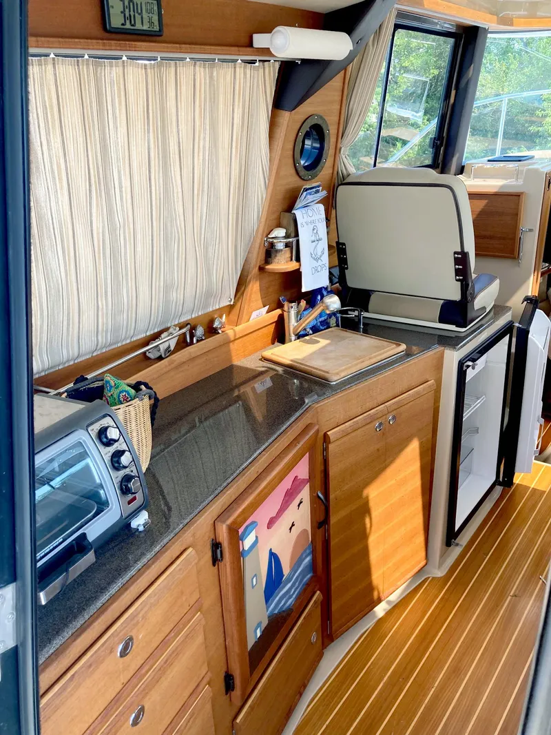 Slide: The Image of 2018 Ranger Tugs R-29 S interior kitchen with wooden cabinetry and appliances. - 6