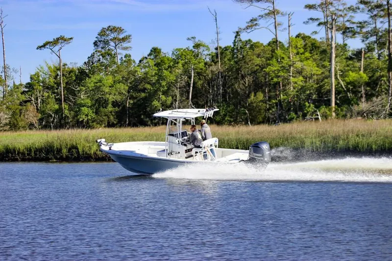Slide: The Image of 2020 BlackJack 256 Bay boat cruising on a scenic river with lush greenery. - 2