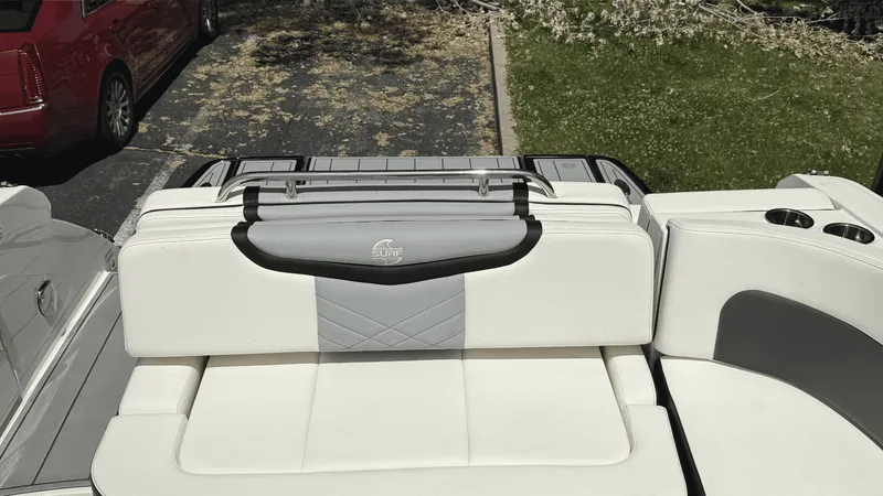 Slide: The Image of 2023 Chaparral 28 Surf boat with white and gray seating, parked outdoors. - 11