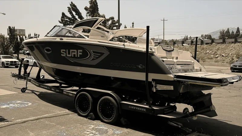 Slide: The Image of 2023 Chaparral 28 Surf boat on trailer, parked outdoors. - 2