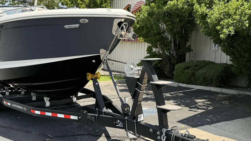 Slide: The Image of 2023 Chaparral 28 Surf boat on trailer, parked outdoors near greenery. - 6