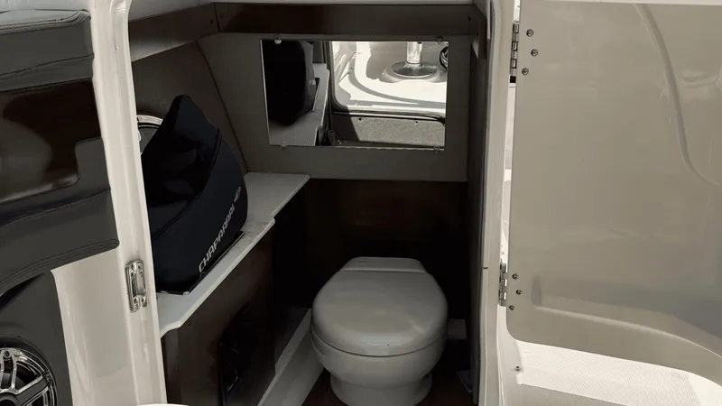 Slide: The Image of 2023 Chaparral 28 Surf boat interior with compact bathroom and storage space. - 9