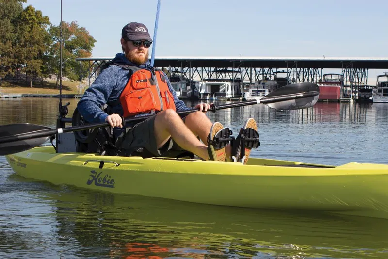 Slide: The Image of Man kayaking on a 2022 Hobie Compass in calm waters near a marina. - 3