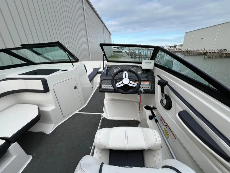 Slide: The Image of 2015 Sea Ray 19 SPX boat interior with steering wheel and seating, docked by the water. - 12
