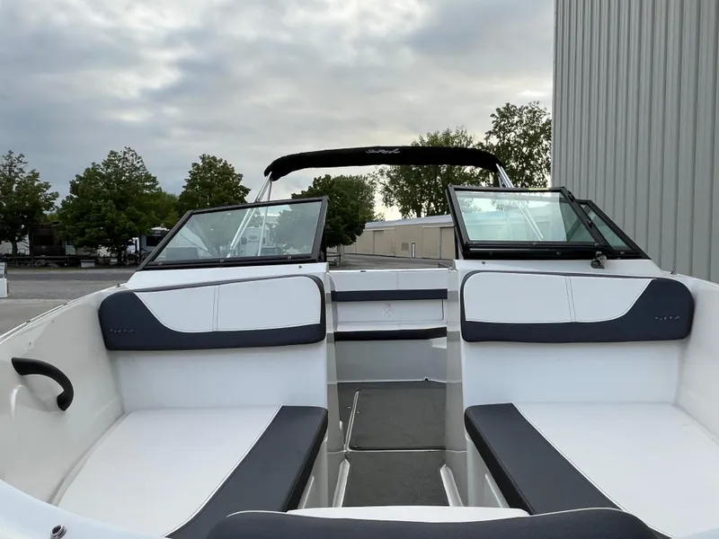 Slide: The Image of 2015 Sea Ray 19 SPX boat interior with white and black seating, docked outdoors. - 17