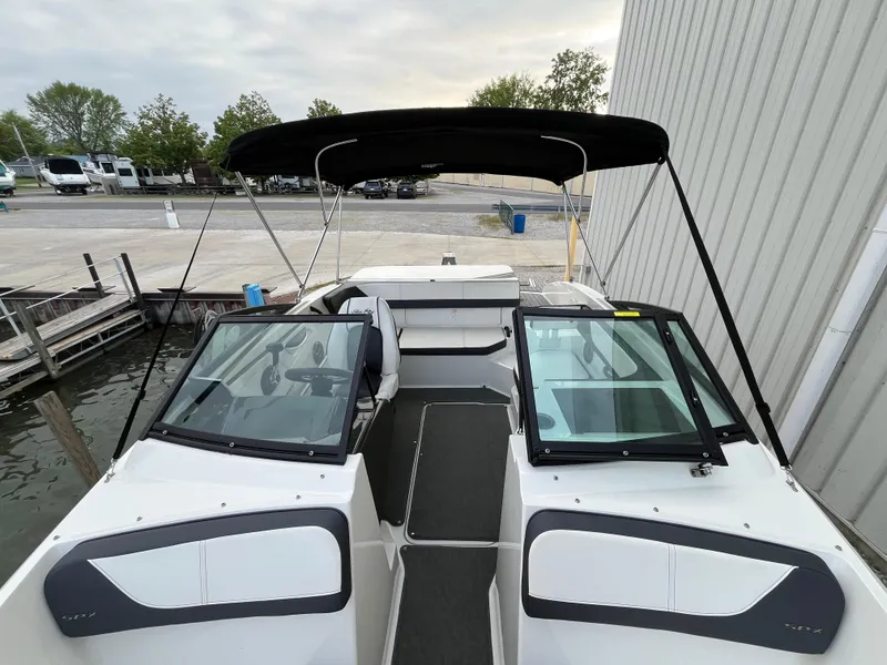 Slide: The Image of 2015 Sea Ray 19 SPX boat with black canopy docked near a marina. - 19