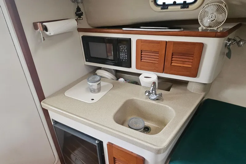 Slide: The Image of 2000 Pursuit 3000 Express boat kitchen with sink, microwave, and storage cabinets. - 11