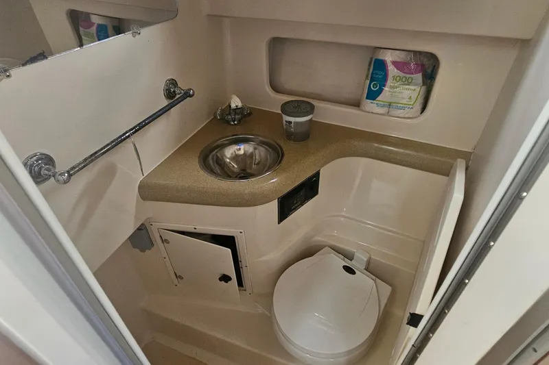 Slide: The Image of Compact bathroom in a 2000 Pursuit 3000 Express boat, featuring sink and toilet. - 14