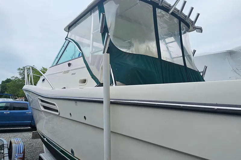 Slide: The Image of 2000 Pursuit 3000 Express boat with green canopy, docked outdoors. - 3