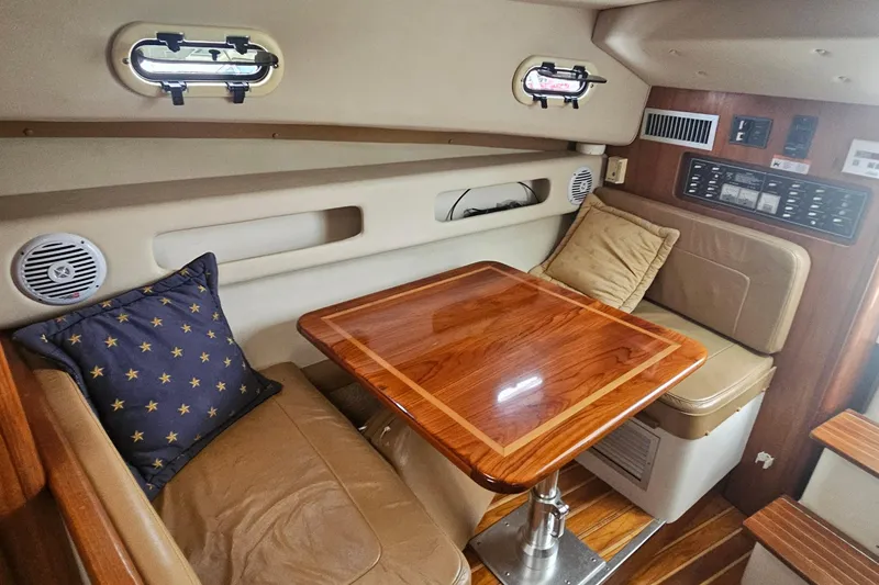 Slide: The Image of 2000 Pursuit 3000 Express cabin interior with wood table, leather seating, and star-patterned pillow. - 9