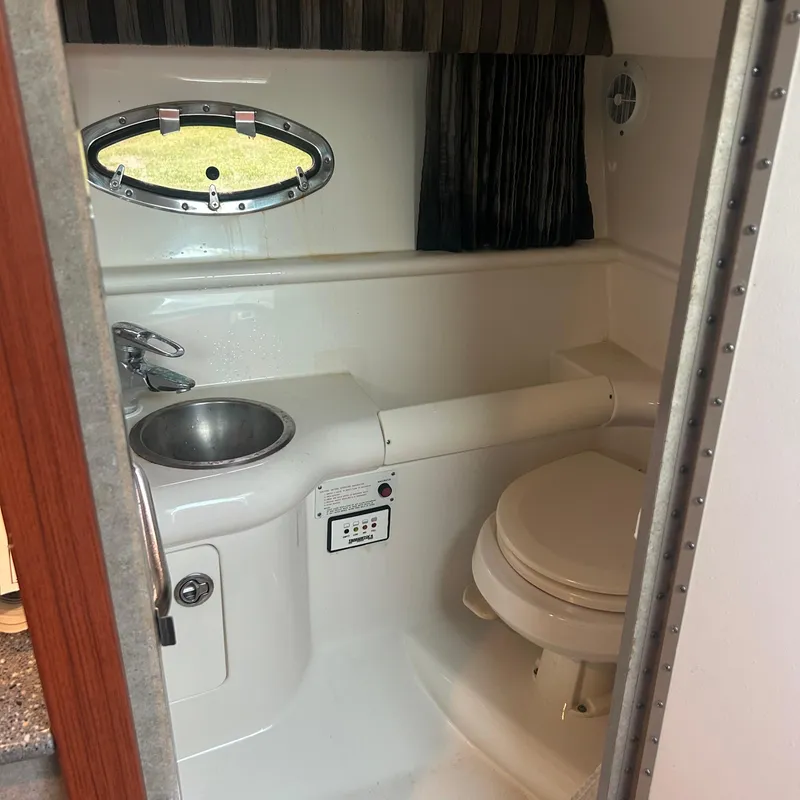 Slide: The Image of 2005 Formula 330 SS boat bathroom with sink, toilet, and porthole window. - 14