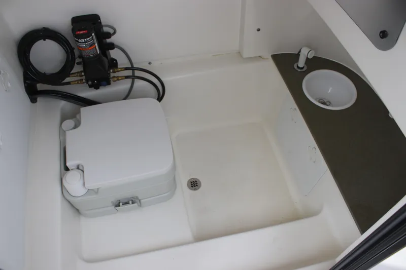 Slide: The Image of 2024 Sea Pro 242 Center Console interior with portable toilet and sink. - 28