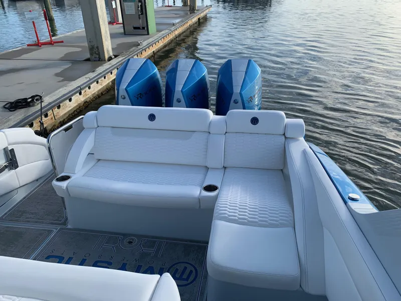 Slide: The Image of 2023 Mystic Powerboats M3800 with triple engines, luxurious seating, docked by the water. - 13