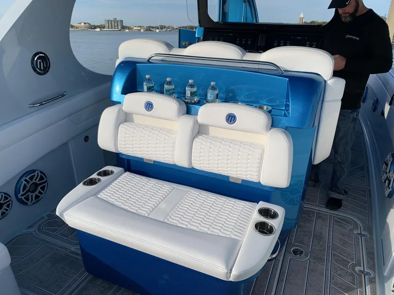 Slide: The Image of 2023 Mystic Powerboats M3800 interior with white seating and cup holders on a luxury boat. - 14