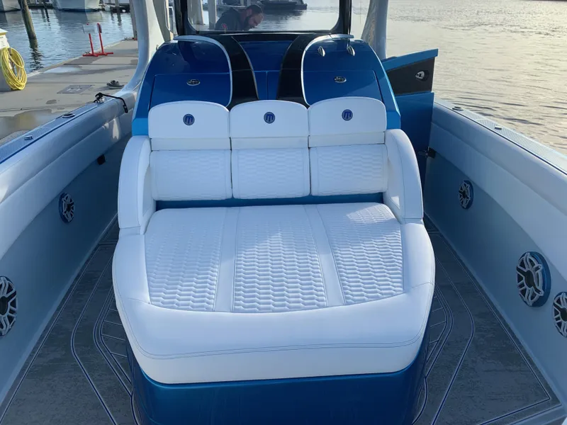 Slide: The Image of 2023 Mystic Powerboats M3800 interior with white and blue seating, dockside view. - 3