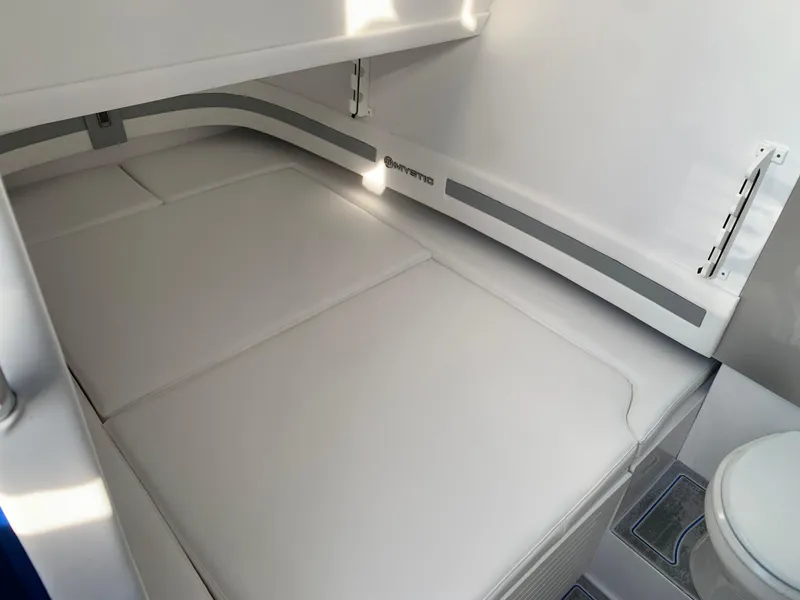 Slide: The Image of 2023 Mystic Powerboats M3800 cabin interior with white cushioned seating and modern design. - 8
