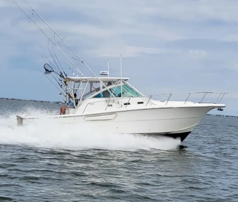 Slide: The Image of 2000 Rampage 38 Express boat cruising on open water, equipped with fishing rods. - 1