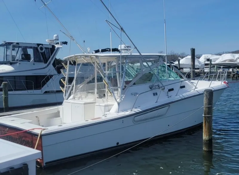 Slide: The Image of 2000 Rampage 38 Express boat docked in marina, clear sky, calm water. - 2