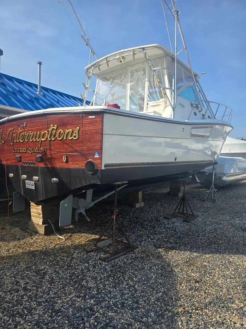 Slide: The Image of 2000 Rampage 38 Express boat on stands, gravel lot, blue roof background. - 3