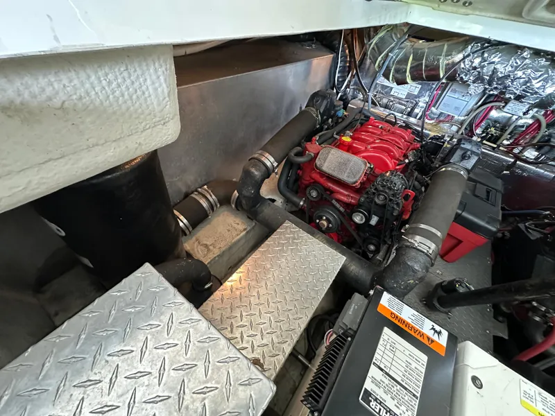 Slide: The Image of Engine room of 2004 Regal Commodore 3860 with visible red engine and metal flooring. - 26
