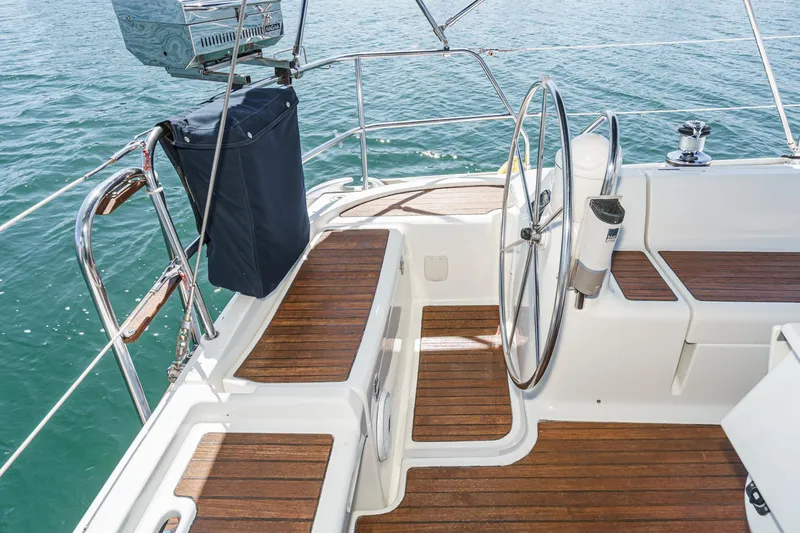 Slide: The Image of Jeanneau Sun Odyssey 43 cockpit with wooden deck, steering wheel, and ocean view. - 25