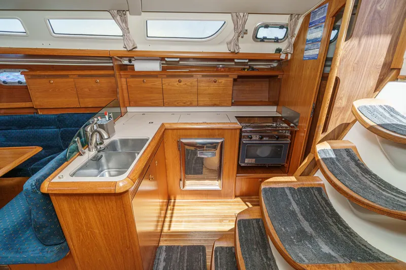 Slide: The Image of Interior of 2002 Jeanneau Sun Odyssey 43 yacht, featuring kitchen and wooden cabinetry. - 44