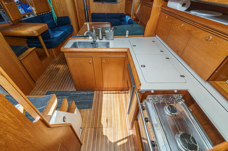 Slide: The Image of Interior of 2002 Jeanneau Sun Odyssey 43 yacht, featuring a wooden kitchen and seating area. - 45