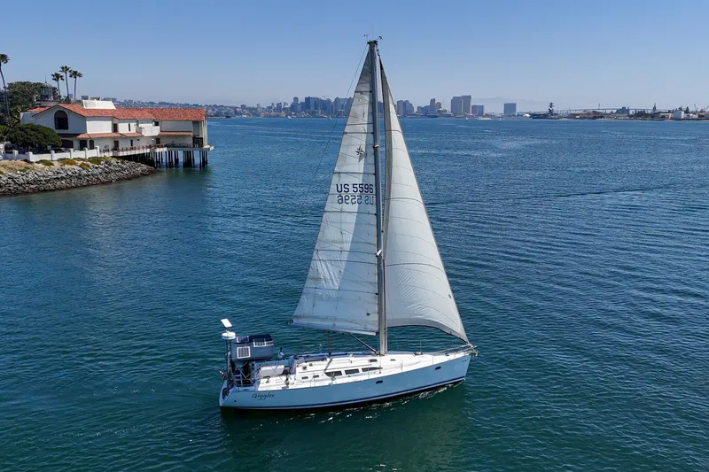 Slide: The Image of Sailboat Jeanneau Sun Odyssey 43, 2002 model, cruising near coastal buildings and city skyline. - 5