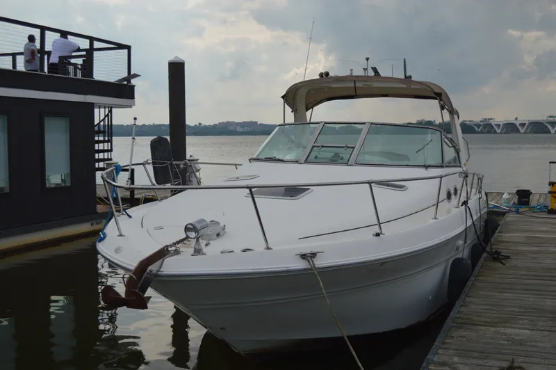 Slide: The Image of 1998 Sea Ray 310 Sundancer docked by a waterfront house, overcast sky. - 15